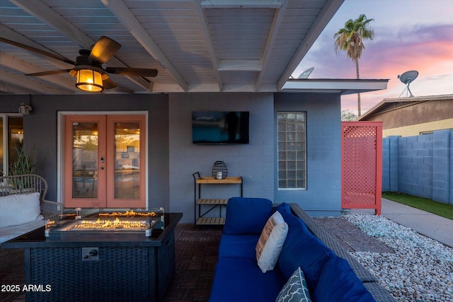 view of patio with ceiling fan, an outdoor living space with a fire pit, and french doors