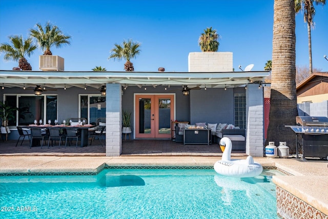 view of swimming pool with ceiling fan, french doors, an outdoor living space, and grilling area