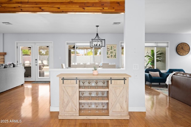 kitchen with french doors, a chandelier, pendant lighting, and hardwood / wood-style flooring