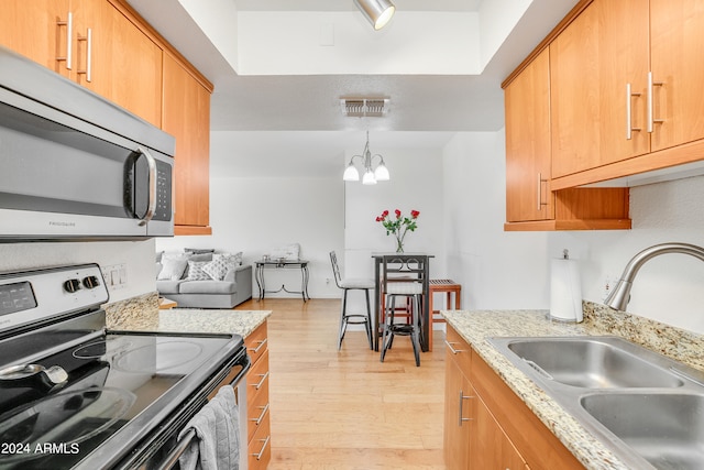 kitchen featuring decorative light fixtures, a notable chandelier, appliances with stainless steel finishes, sink, and light hardwood / wood-style flooring