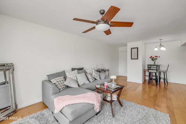 living room with ceiling fan with notable chandelier and light hardwood / wood-style floors