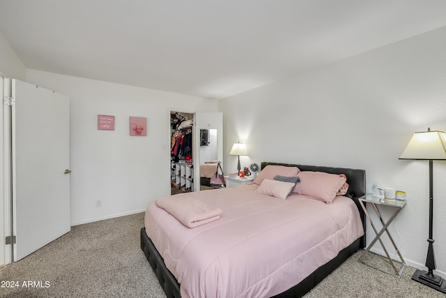 bedroom with a closet, a spacious closet, and light colored carpet