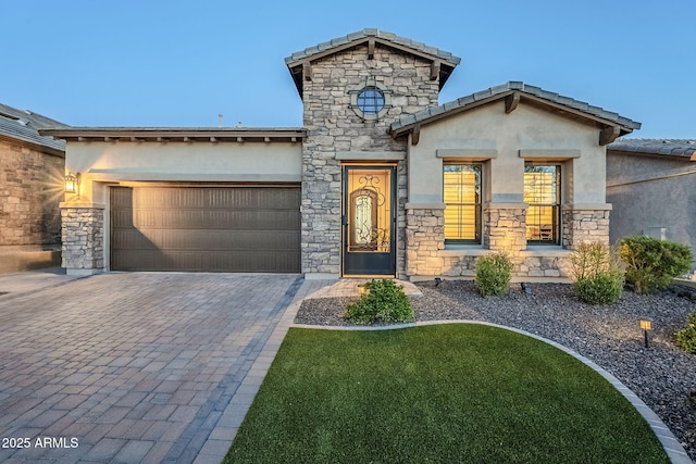 view of front of property with decorative driveway, an attached garage, and stucco siding