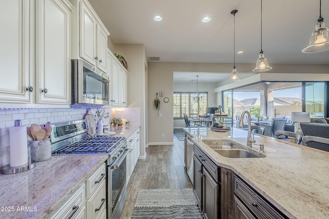 kitchen featuring a sink, white cabinetry, appliances with stainless steel finishes, light stone countertops, and tasteful backsplash