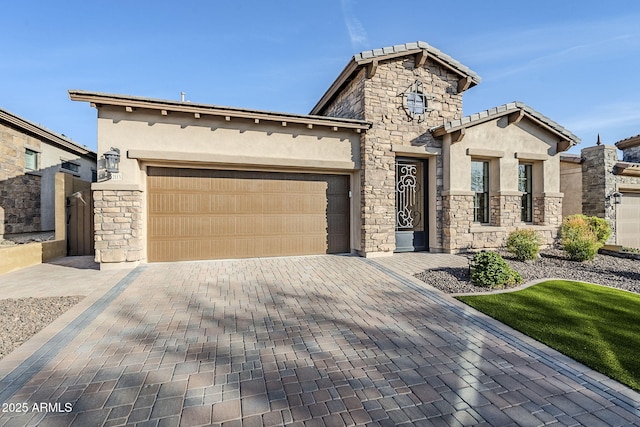 view of front of house featuring decorative driveway, stone siding, an attached garage, and stucco siding