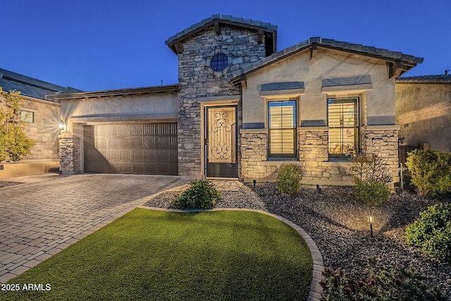 view of front of home featuring a garage, stone siding, decorative driveway, and stucco siding