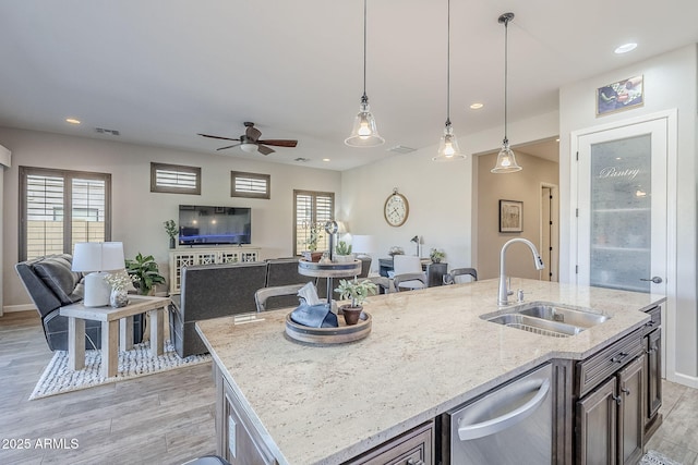 kitchen featuring a sink, visible vents, open floor plan, an island with sink, and decorative light fixtures