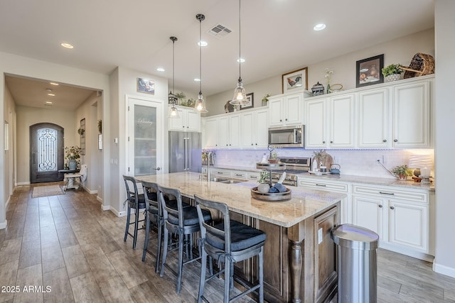 kitchen with visible vents, appliances with stainless steel finishes, white cabinets, and a sink