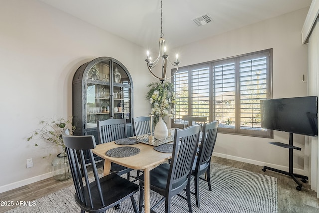 dining space featuring a chandelier, visible vents, baseboards, and wood finished floors