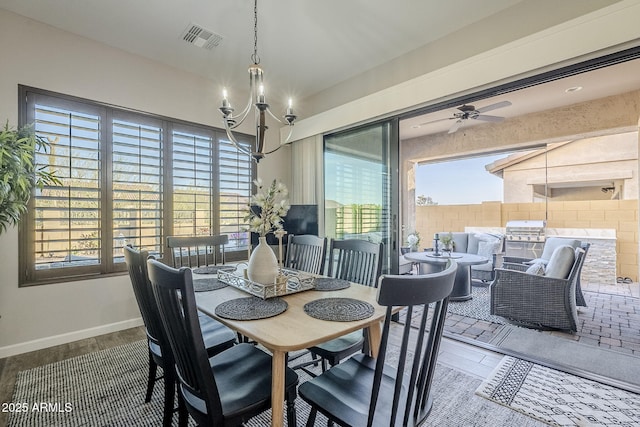 dining space with wood finished floors, visible vents, baseboards, and ceiling fan with notable chandelier