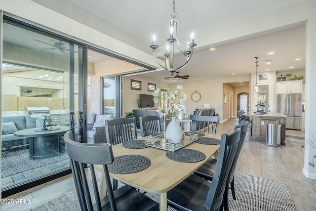 dining space with ceiling fan with notable chandelier, arched walkways, and recessed lighting