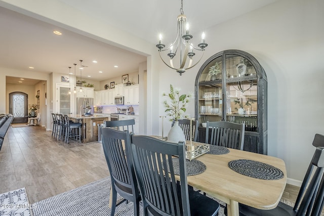 dining room with a chandelier, light wood finished floors, baseboards, and recessed lighting