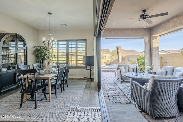 dining room featuring baseboards, visible vents, wood finished floors, and ceiling fan with notable chandelier