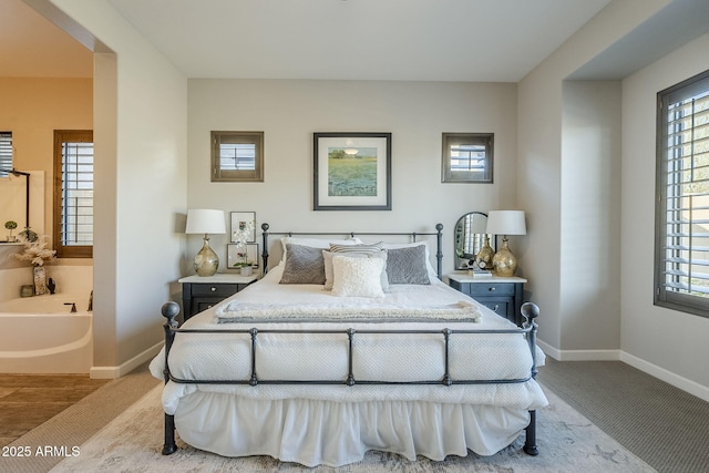 carpeted bedroom featuring ensuite bath and baseboards