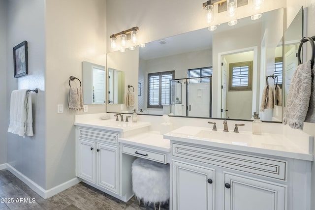 bathroom featuring a sink, a shower stall, baseboards, and double vanity