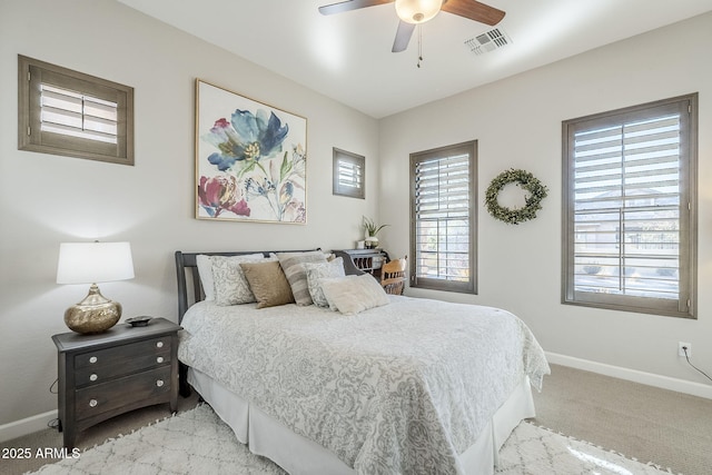 bedroom with light carpet, ceiling fan, visible vents, and baseboards