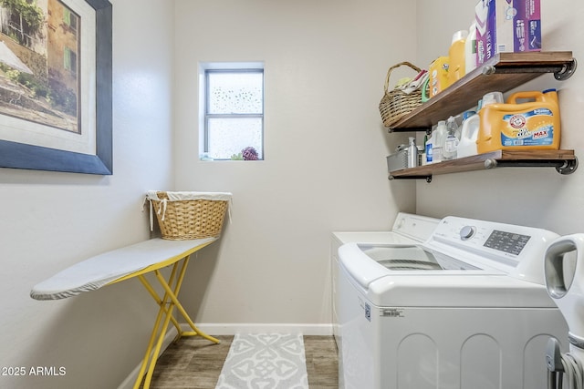 laundry area with laundry area, baseboards, washer and dryer, and wood finished floors