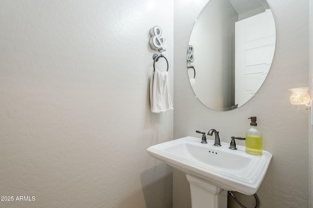 bathroom featuring a textured wall and a sink