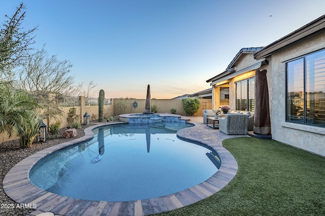 pool at dusk with a fenced backyard, a pool with connected hot tub, and a patio