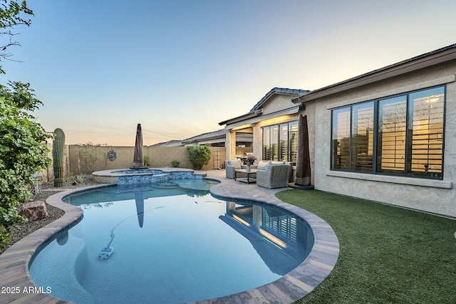 pool at dusk with a fenced backyard, a pool with connected hot tub, and a patio