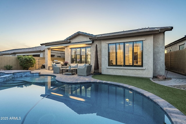 back of house at dusk featuring a fenced backyard, an outdoor hangout area, and stucco siding