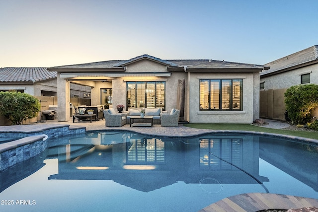 back of property featuring outdoor lounge area, fence, a pool with connected hot tub, stucco siding, and a patio area