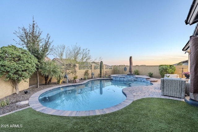 pool at dusk with a fenced backyard, a pool with connected hot tub, a patio, and a yard