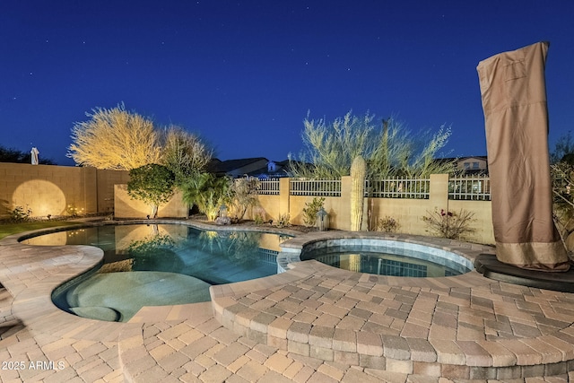 pool at twilight with a fenced in pool, a fenced backyard, a patio, and an in ground hot tub