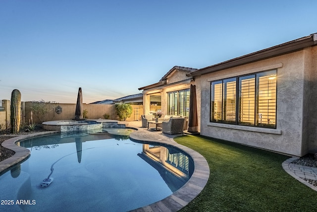 pool at dusk featuring a yard, a pool with connected hot tub, an outdoor hangout area, a patio area, and a fenced backyard