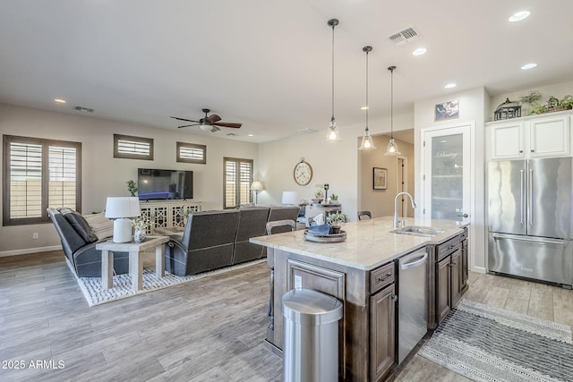 kitchen featuring appliances with stainless steel finishes, visible vents, a sink, and light stone counters