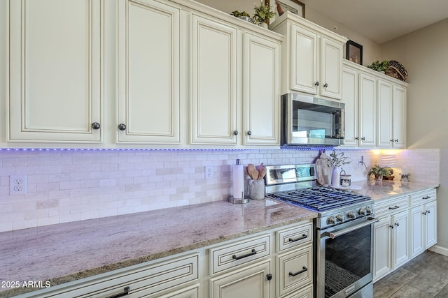 kitchen featuring appliances with stainless steel finishes, backsplash, and light stone counters