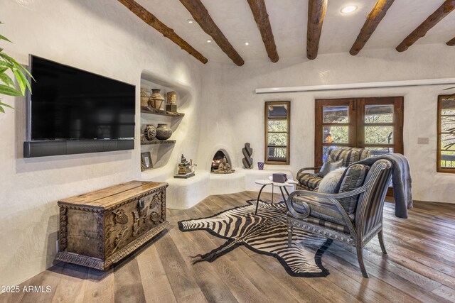 living area with built in features, beamed ceiling, and wood finished floors