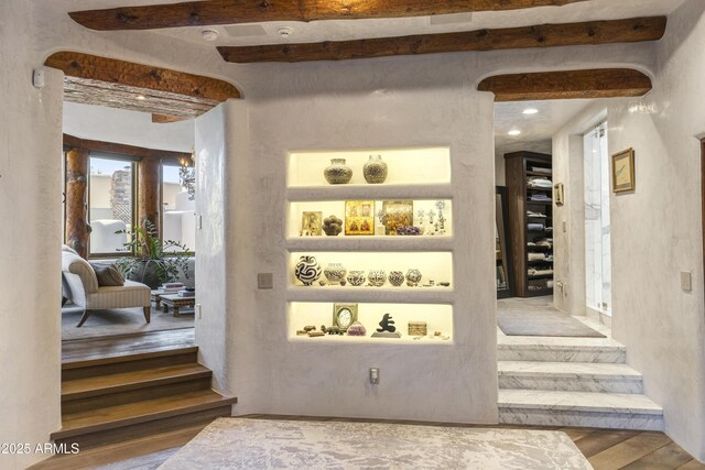 wine cellar featuring built in features, beam ceiling, and wood finished floors