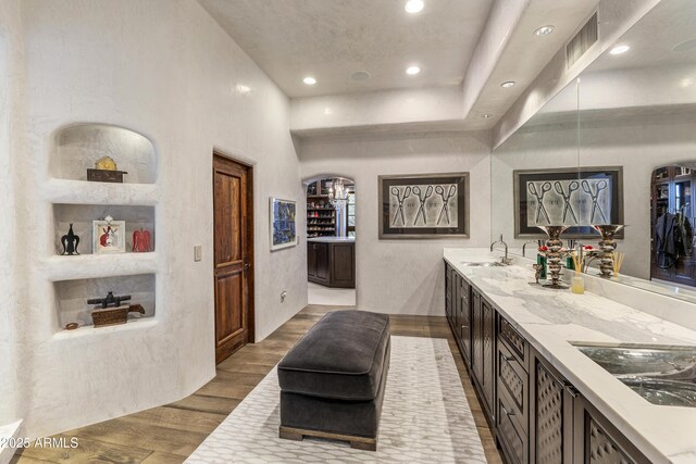 full bath with double vanity, recessed lighting, visible vents, a sink, and wood finished floors