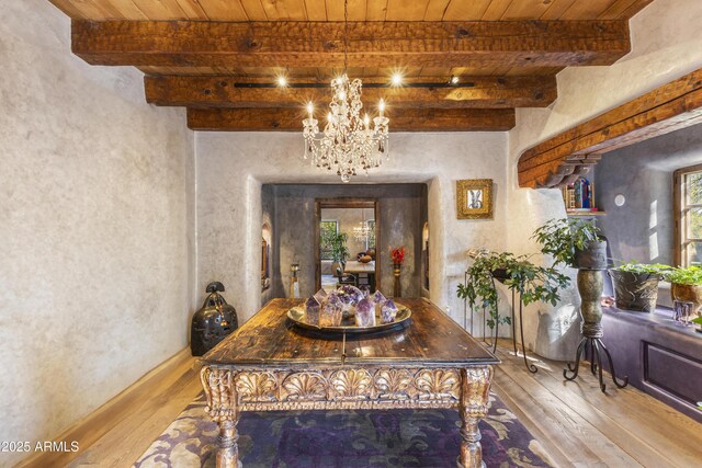 dining space featuring wood ceiling, wood finished floors, beam ceiling, and an inviting chandelier