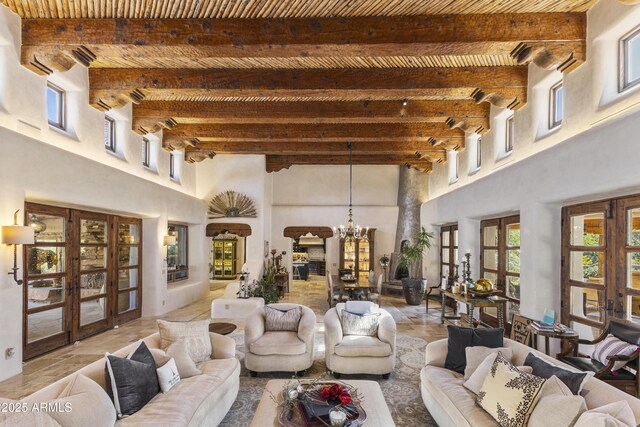 living room featuring french doors, plenty of natural light, beam ceiling, and an inviting chandelier