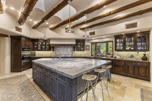 kitchen featuring dark brown cabinetry, visible vents, glass insert cabinets, decorative light fixtures, and a sink