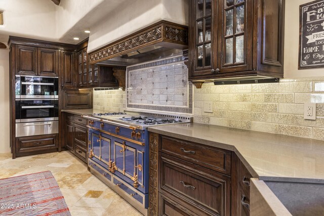 kitchen featuring glass insert cabinets, a warming drawer, appliances with stainless steel finishes, and custom exhaust hood