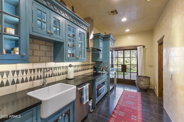 kitchen with a sink, visible vents, blue cabinetry, stainless steel dishwasher, and wall chimney exhaust hood