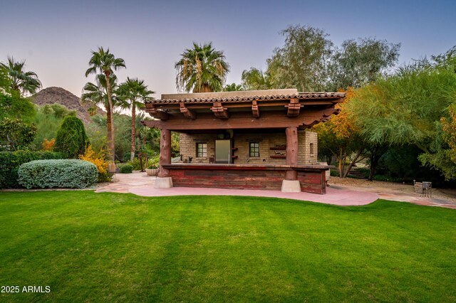 back of house at dusk featuring a yard and a patio area