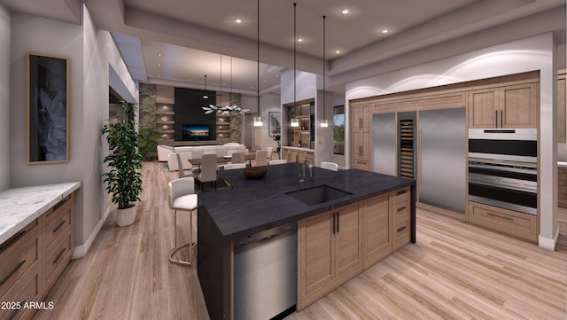 kitchen featuring appliances with stainless steel finishes, sink, dark stone countertops, hanging light fixtures, and a large island