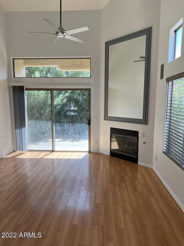 9070 E Gary Rd Unit 152, Scottsdale, AZ 85260 - unfurnished living room featuring a high ceiling, a glass covered fireplace, a ceiling fan, and wood finished floors