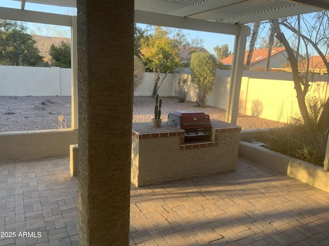 view of patio / terrace with area for grilling, a pergola, and exterior kitchen