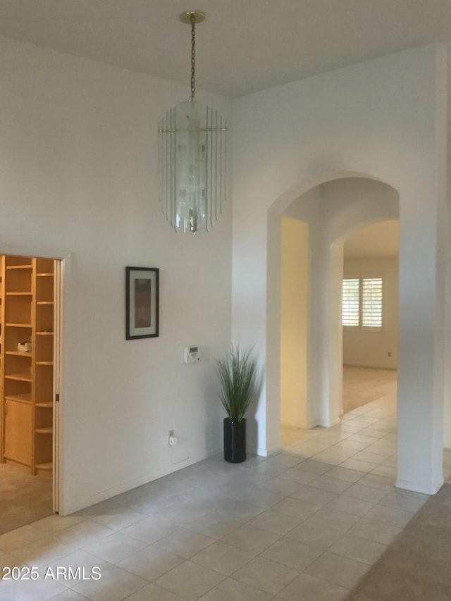 tiled spare room featuring a notable chandelier