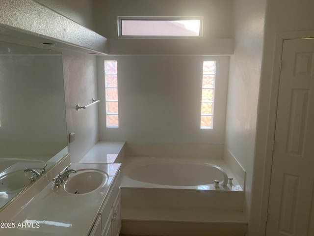 bathroom with vanity, plenty of natural light, and a tub