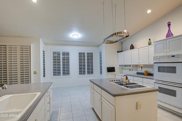 kitchen with white cabinetry, sink, a center island with sink, and double oven