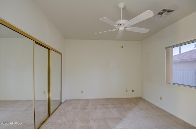 unfurnished bedroom featuring ceiling fan, light colored carpet, and a closet