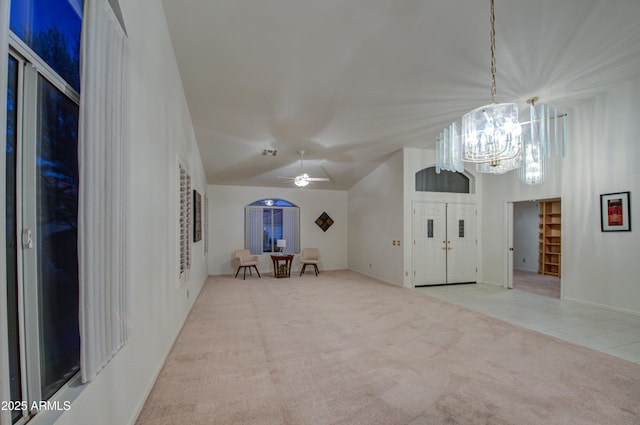unfurnished living room with lofted ceiling, ceiling fan with notable chandelier, and light colored carpet
