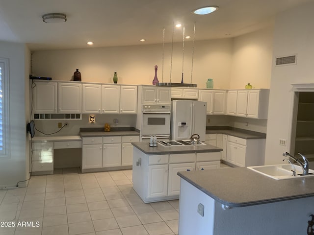 kitchen featuring sink, a center island, white cabinets, white refrigerator with ice dispenser, and a high ceiling