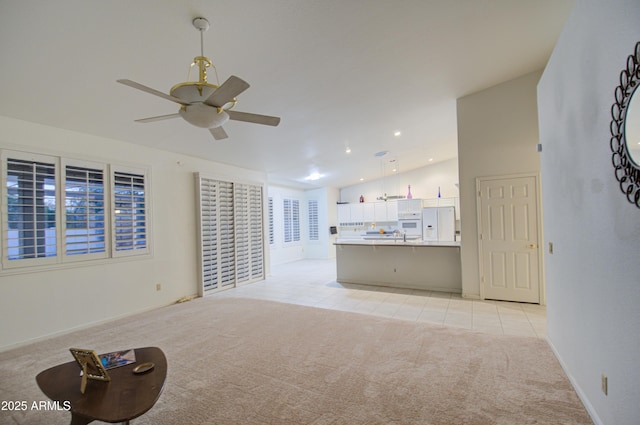 unfurnished living room featuring vaulted ceiling, light carpet, and ceiling fan